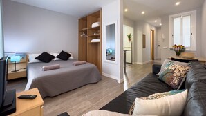 Une chambre d’hôtel moderne équipée d’un lit, d’un canapé, d’une télévision et d’un bureau.