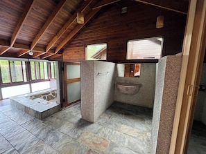 A bathroom with stone flooring, a wooden ceiling, and a window. - Watervilla (Puli)