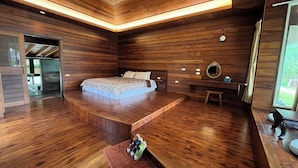 Ein modernes Schlafzimmer mit Holzboden, einem Bett mit Kopfteil, einem Nachttisch und einem Spiegel.