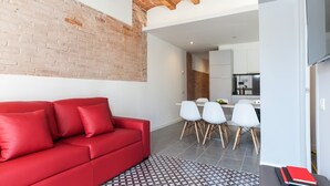 Una sala de estar moderna con un sofá rojo, sillas blancas y una alfombra estampada.