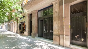 Una calle con un edificio de fachada de piedra y grandes puertas negras.