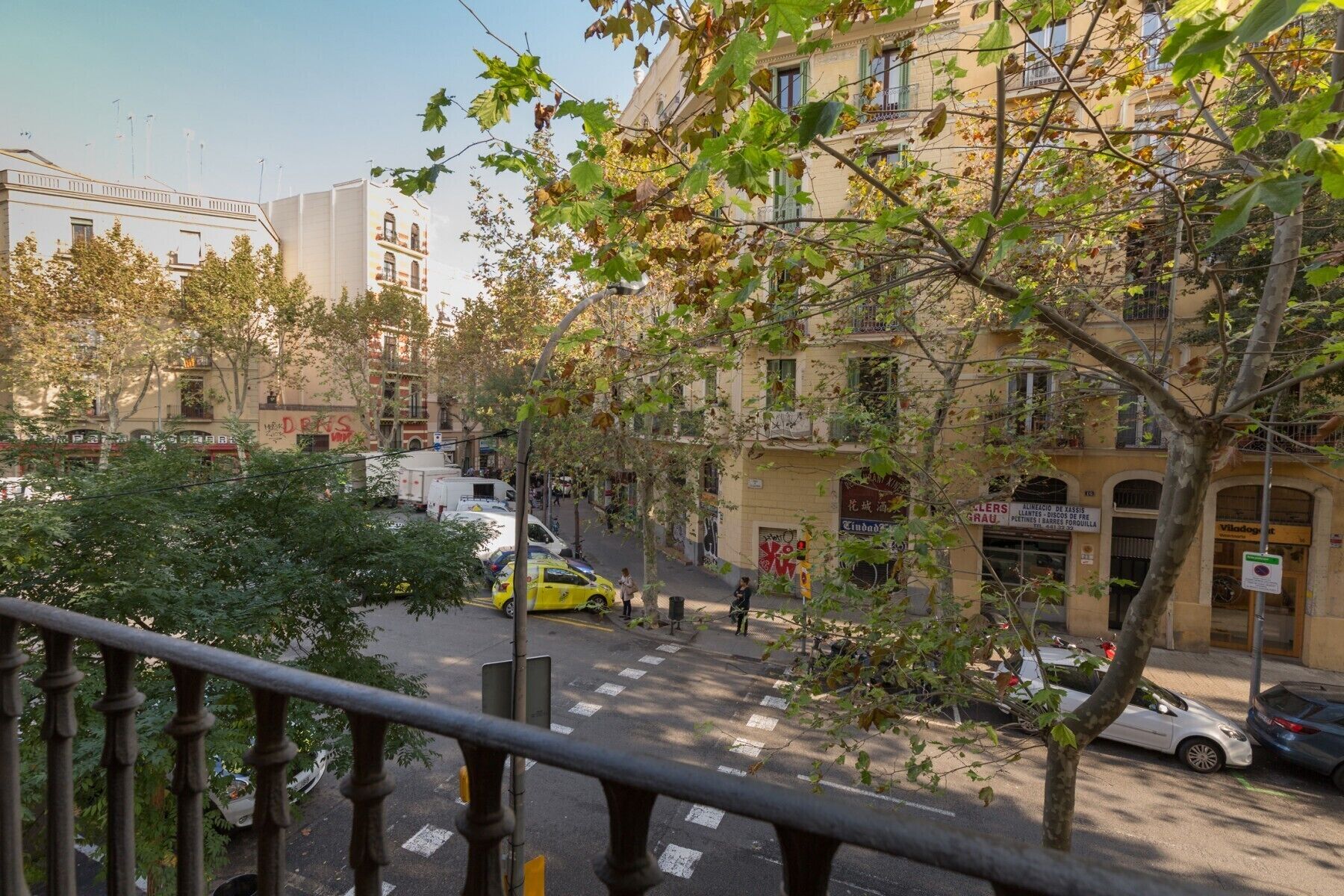 Vista da rua com prédios, faixa de pedestres e carros estacionados.