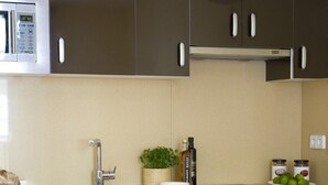 Una cocina moderna con armarios oscuros, un microondas de acero inoxidable, un lavabo y un comedor con mesa y sillas.