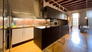Une cuisine moderne avec un mur de fond en briques, des appareils électroménagers en acier inoxydable et un plancher en bois.