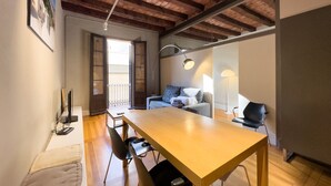 Un salon chaleureux avec une table en bois, un canapé et un fauteuil. Il y a un balcon avec vue.