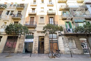 A multi-story building with balconies, a bicycle parked in front, and a storefront with a sign. - GRACIA DREAM, very nice restored vacation rental apartment in Barcelona center, Gracia (Barcelona)