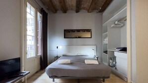 Ein modernes Hotelzimmer mit einem großen Bett, einem Flachbildfernseher, einem kleinen Tisch und einem Kleiderschrank.