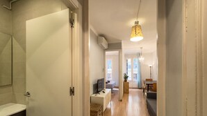 A hallway leading to a bedroom with a TV, a desk, and a dining area. - Cute, quiet and lightly apartment with balcony for rent in Barcelona center, Gracia (Barcelona)