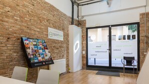 A modern interior with a brick wall, a welcome sign, and a glass door leading outside. - Cute, quiet and lightly apartment with balcony for rent in Barcelona center, Gracia (Barcelona)