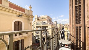 Ein Balkon mit Blick auf angrenzende Gebäude, darunter ein Gebäude mit einem Balkon und ein Gebäude mit einem Fenster mit Rollläden.