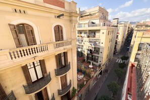 Un edificio de varios pisos con balcones, vista a la calle y cielo despejado.