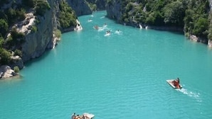 Une rivière bordée de falaises, avec des bateaux et des gens.