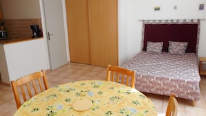 Une pièce de taille modeste comprenant un lit, une table à manger et un coin cuisine.