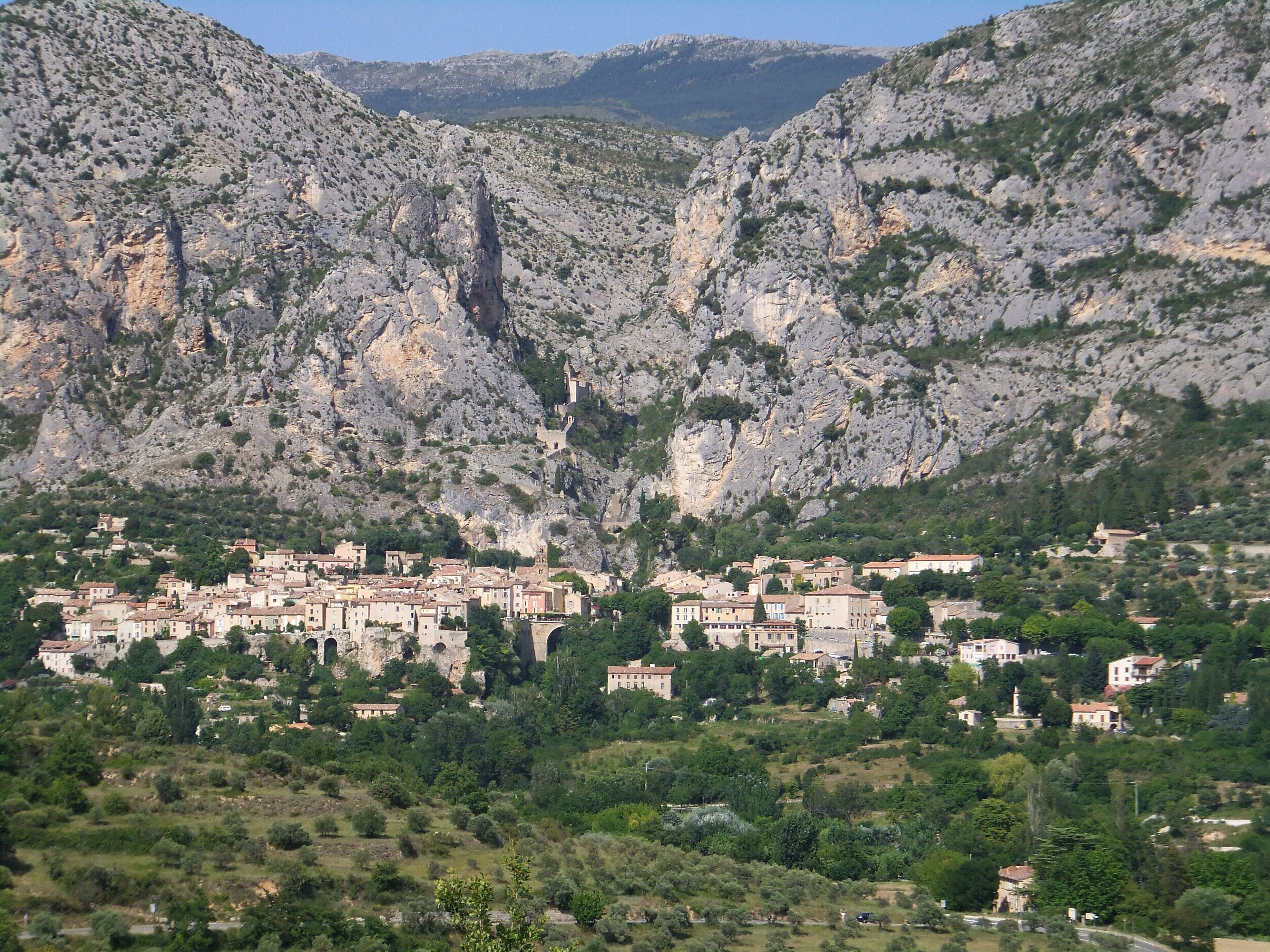 A town nestled in a valley with historic stone buildings, surrounded by rugged mountains.