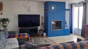 Un salon doté d’un téléviseur à écran plat, d’un mur d’accent bleu et d’un lustre moderne.