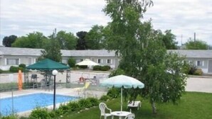 En swimmingpool med rutsjebane, omgivet af en græsplæne med hvide stole og et bord.