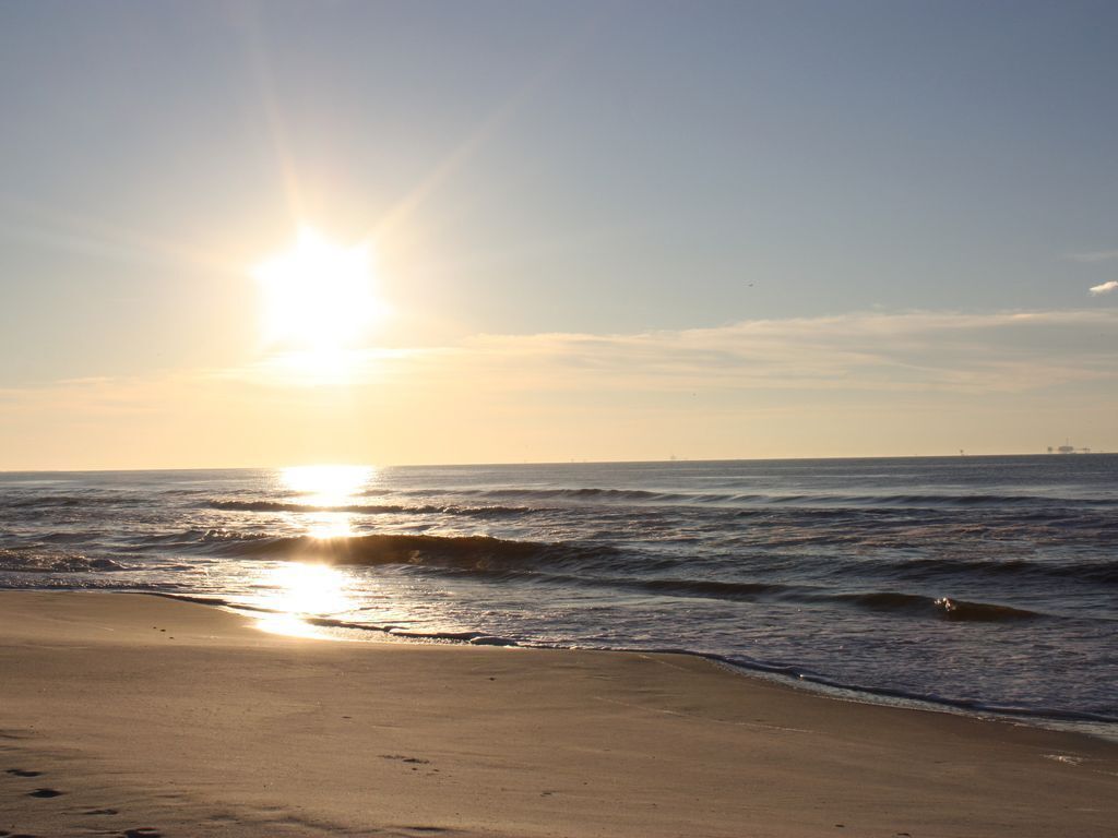 Une plage où le soleil se couche sur l’océan, créant une atmosphère paisible.