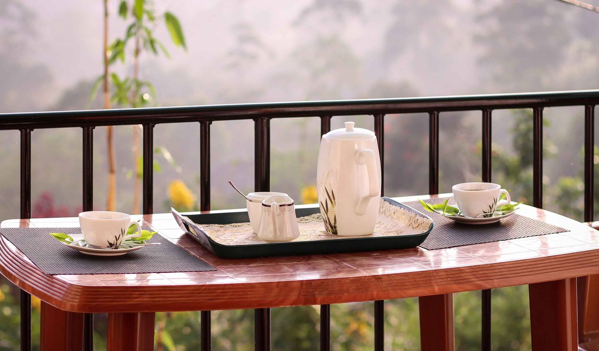 A wooden table with a tray holding a teapot, cups, and a sugar bowl.