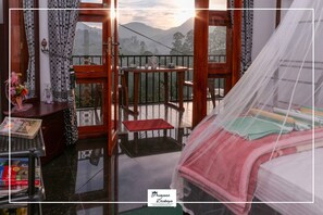A room with a bed, a small table with cups and a teapot, a balcony with a view of mountains, and a window with curtains. - Princess of Dickoya (Dickoya)