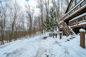 Un bâtiment en bois avec un escalier menant à une terrasse, entouré d’arbres couverts de neige.