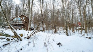 Une cabane en bois, entourée d’un paysage enneigé, avec une pancarte indiquant l’entrée.