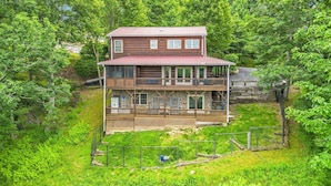 Une cabane en rondins à deux étages, dotée d’un balcon et entourée d’une végétation luxuriante.