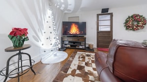 A living room with a fireplace, a television, a Christmas wreath, and a leather sofa.
