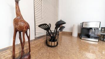 A kitchen with a wooden giraffe sculpture, a coffee machine, and a utensil holder.
