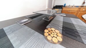 A dining table with a glass top, a notebook, and a decorative wooden piece.