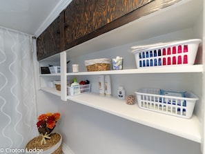 Laundry room with shelving units and storage for linens and supplies.