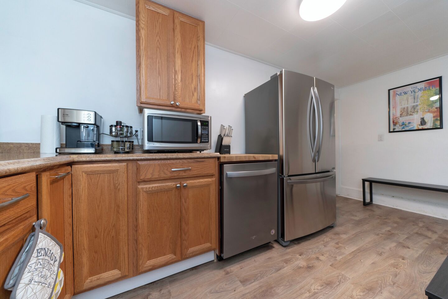 A modern kitchen with wooden cabinets, stainless steel appliances, and a bench.