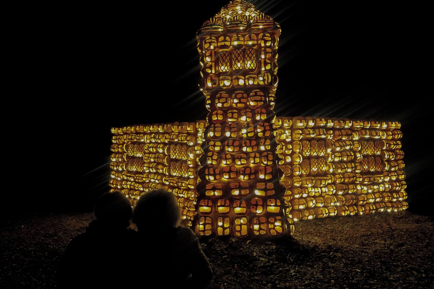Une grande structure illuminée, qui ressemble à un bâtiment doté d’une tour, vue de loin.