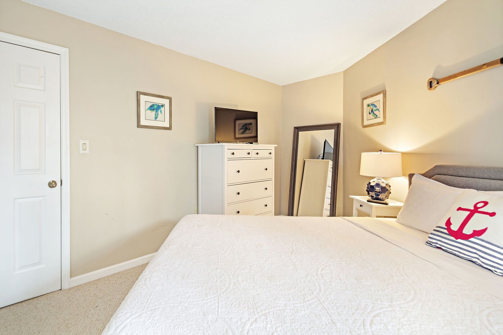 Un dormitorio con cama, cómoda, espejo, lámpara y almohadas decorativas.