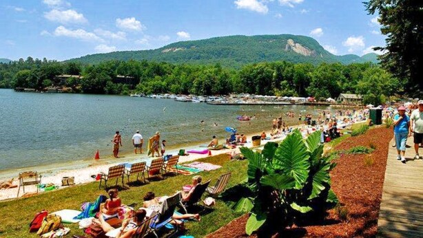 Un complexe hôtelier au bord d’un lac, doté d’une pelouse, de chaises longues et offrant une vue sur le lac et les montagnes.