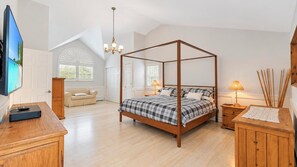 A bedroom with a four-poster bed, a wooden dresser, a television, and a window with blinds. - Secluded Wainscott Estate with Heated Pool, Hot Tub, Expansive Yard &... (Wainscott)