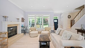 Uma sala de estar ampla com lareira, assentos confortáveis e grandes janelas com vista para o exterior.