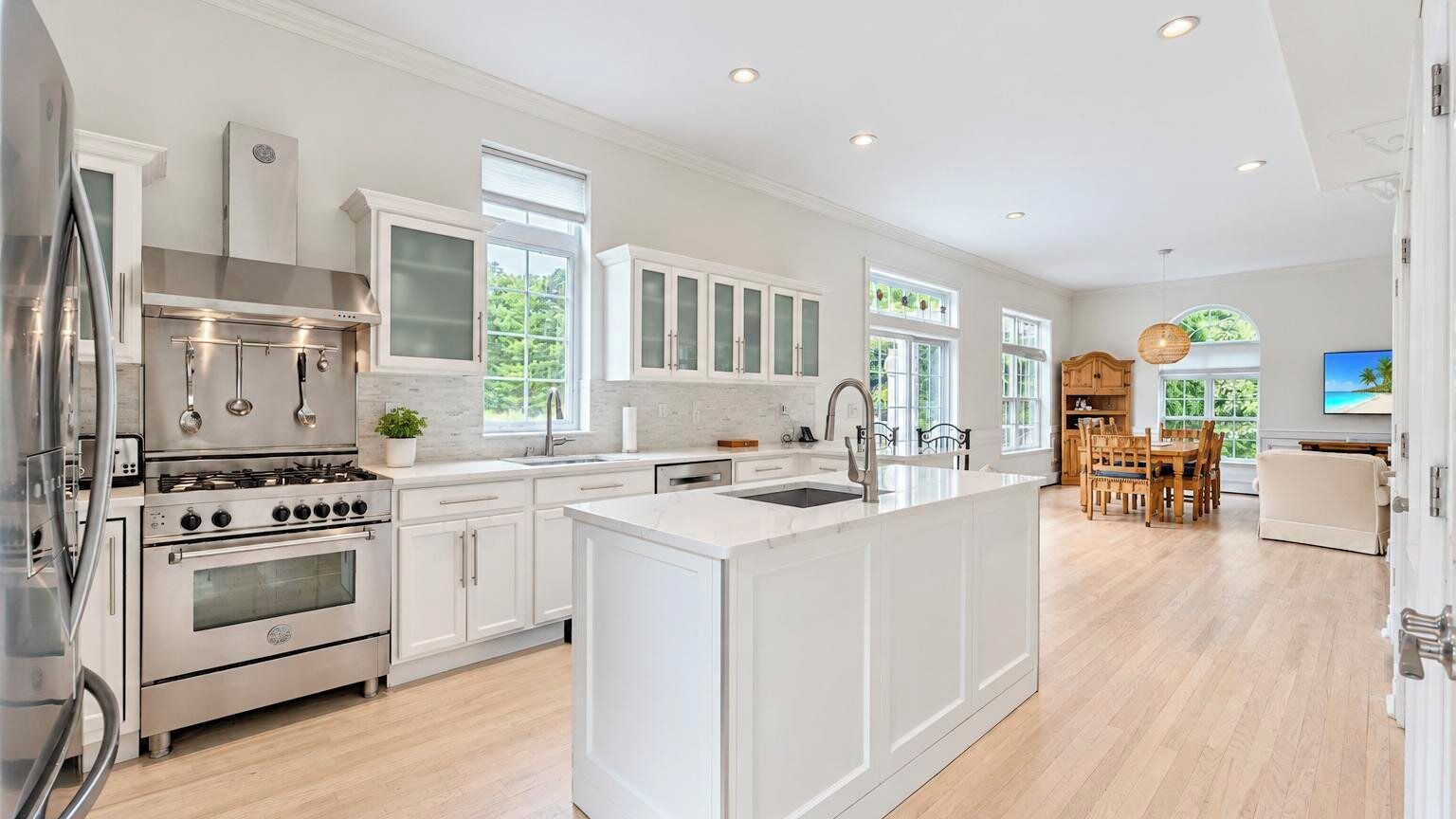 A modern kitchen with white cabinetry, stainless steel appliances, and a central island.