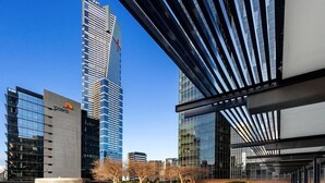 Un bâtiment moderne doté d’une façade en verre incurvée, entouré d’une pelouse bien entretenue et de quelques arbres.