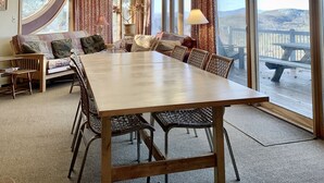 A spacious dining area with a large wooden table and chairs, large windows with curtains, and a ceiling fan. - Spacious Mtn Top Contemporary - Spectacular Views - in Waterville Estates (Campton)