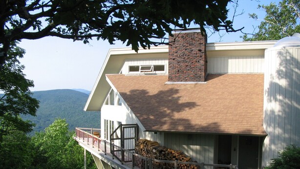 A house with a large balcony, a chimney, and a view of the mountains. - Spacious Mtn Top Contemporary - Spectacular Views - in Waterville Estates (Campton)