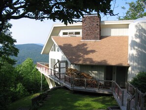 Une maison dotée d’un grand balcon, d’une cheminée et offrant une vue sur les montagnes.