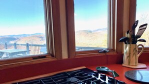 A kitchen with a gas stove, a window with a view of hills, and a utensil holder on the windowsill. - Spacious Mtn Top Contemporary - Spectacular Views - in Waterville Estates (Campton)