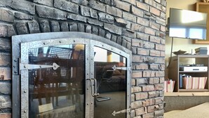 A brick wall with a metal-framed glass door, a sofa, and a shelf with items. - Spacious Mtn Top Contemporary - Spectacular Views - in Waterville Estates (Campton)