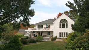 Une maison à deux étages avec un porche à l’avant, un patio couvert et un escalier menant à l’étage supérieur.