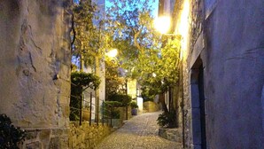 A narrow cobblestone alleyway flanked by stone walls and trees, with a street lamp providing light. - The only one with a pool in downtown Tossa. Beach 100 m away, sleeps 6, Wi-Fi, renovated (Tossa de Mar)