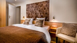 A hotel room with a large bed, two bedside tables, a chair, and a geometric-patterned headboard. - Bergkristal, premium apartment located in Epen - South Limburg. (Epen)
