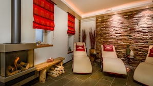 A spa room with a fireplace, two massage chairs, a stone wall, and a wooden bench with logs. - Bergkristal, premium apartment located in Epen - South Limburg. (Epen)
