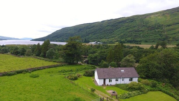 A white house with a tiled roof, surrounded by lush green fields and a hill in the background. - Quiet location with stunning views, sleeps 8, pet friendly, free Wi-Fi (Cairndow)