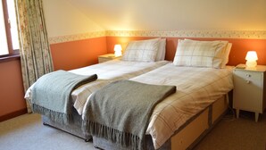A double bed with a grey blanket, two bedside tables with lamps, and a window with curtains. - Quiet location with stunning views, sleeps 8, pet friendly, free Wi-Fi (Cairndow)