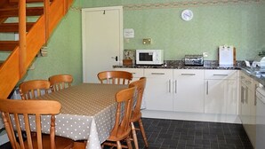 A kitchen with a dining table, chairs, a microwave, a radio, and a clock on the wall. - Quiet location with stunning views, sleeps 8, pet friendly, free Wi-Fi (Cairndow)